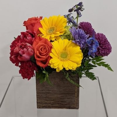 A veritable kaleidoscope of color, this dazzling bouquet is sure to make a grand entrance. This fantastic combination of colorful roses, tulips, gerbers, delphinium, chrysanthemums and more is perfectly arranged in a wooden cube. This lovely bouquet is hand-arranged and hand-delivered to your door.